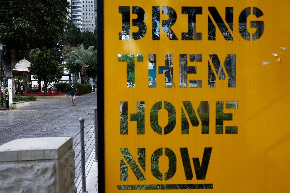 A man walks near a board with a slogan calling for the return of hostages kidnapped in the deadly October 7 attack on Israel by the Palestinian Islamist group Hamas from Gaza, in Tel Aviv April 6, 2024. — Reuters pic  