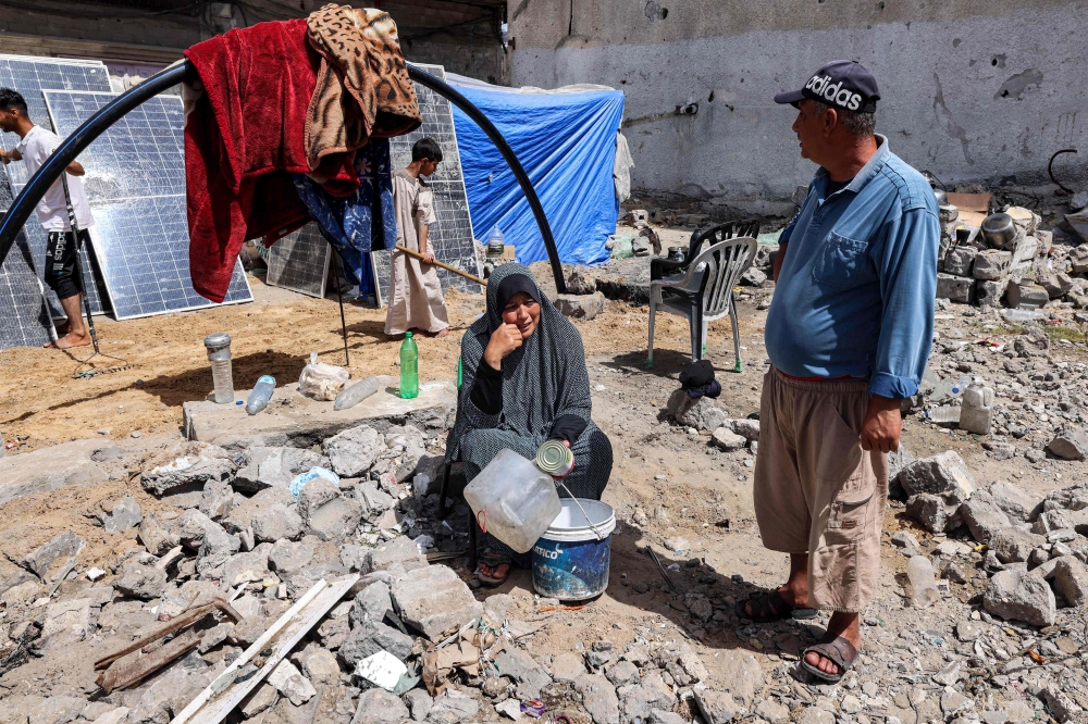 A woman sits holding empty containers outside a tent pitched by a destroyed building in Rafah in the southern Gaza Strip on April 5, 2024 amid the ongoing conflict in the Palestinian territory between Israel and Hamas. — AFP pic