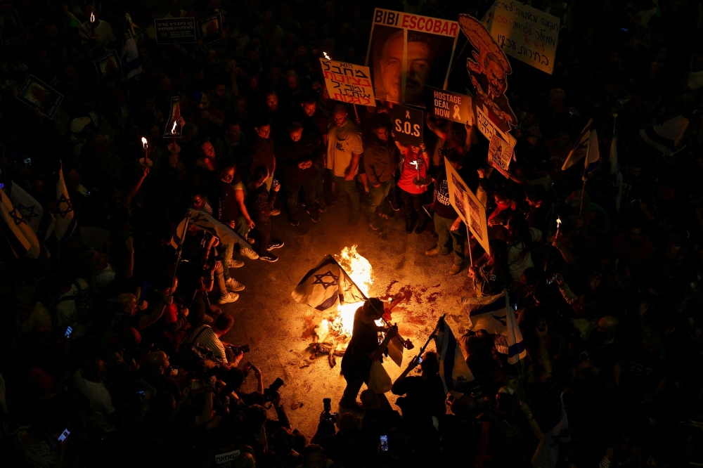 People gather near a fire during a protest against Israeli Prime Minister Benjamin Netanyahu’s government and to call for the release of hostages kidnapped in the deadly October 7 attack on Israel by Hamas from Gaza, in Tel Aviv, Israel, April 7, 2024. — Reuters pic