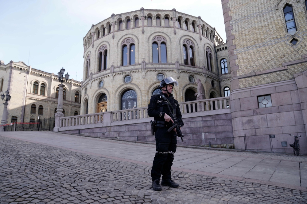File photo of an armed Police officer patrolling the area outside the Norwegian Parliament building On April 3, 2024. — AFP pic