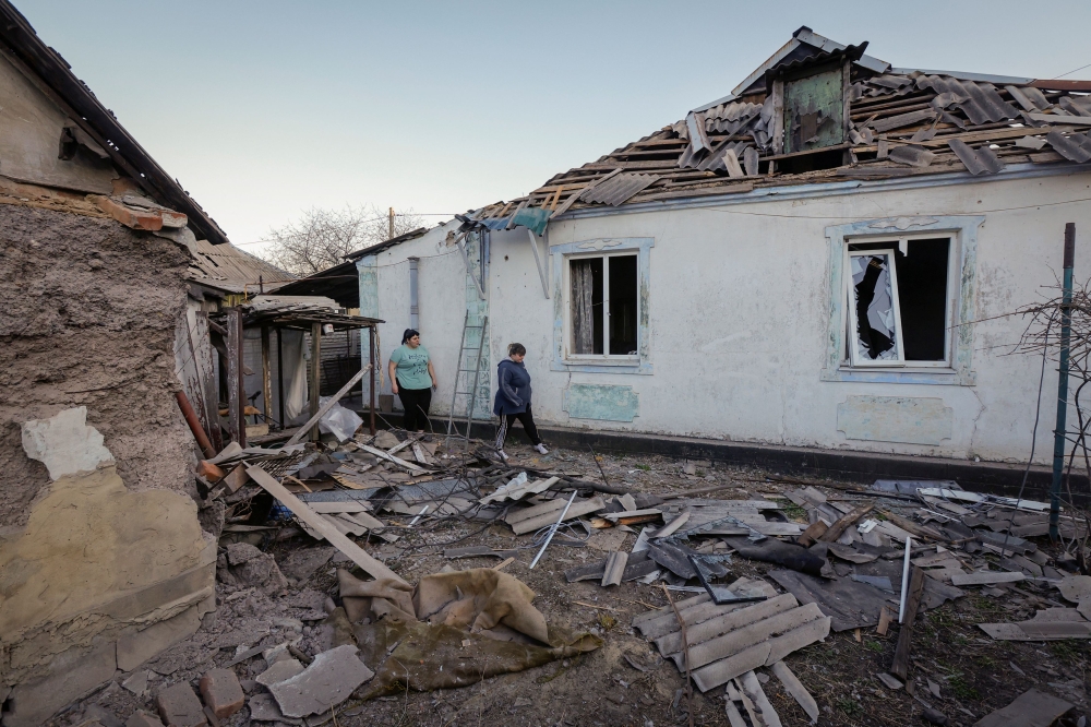 Sisters Ekaterina and Tatyana Nikonorova walk next to their house, which was damaged during a recent shelling in the course of the Russia-Ukraine conflict, in Donetsk, Russian-controlled Ukraine, April 6, 2024. — Reuters pic