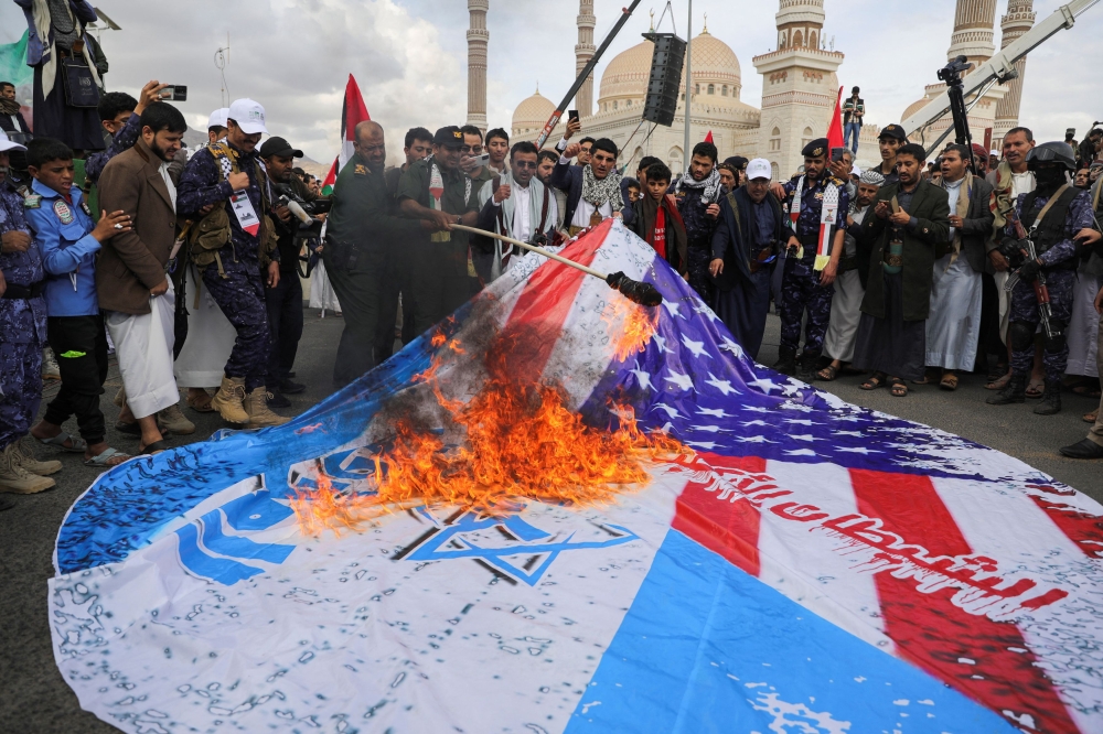 Protesters, mainly Houthi supporters, burn a poster with US and Israeli flags during a rally marking the annual al-Quds Day (Jerusalem Day) on the last Friday of the holy month of Ramadan in Sanaa, Yemen April 5, 2024. — Reuters pic