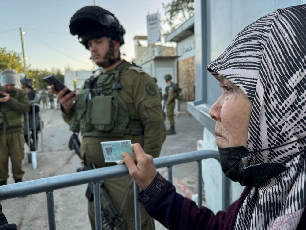 An Israeli army soldier checks Palestinian ID cards, as Palestinians queue at an Israeli checkpoint, to make their way to Jerusalem's al- Aqsa compound, also known to Jews as the Temple Mount, to attend the last Friday prayers during the Muslim holy fasting month of Ramadan, in Bethlehem in the Israeli-occupied West Bank, April 5, 2024. — Reuters pic