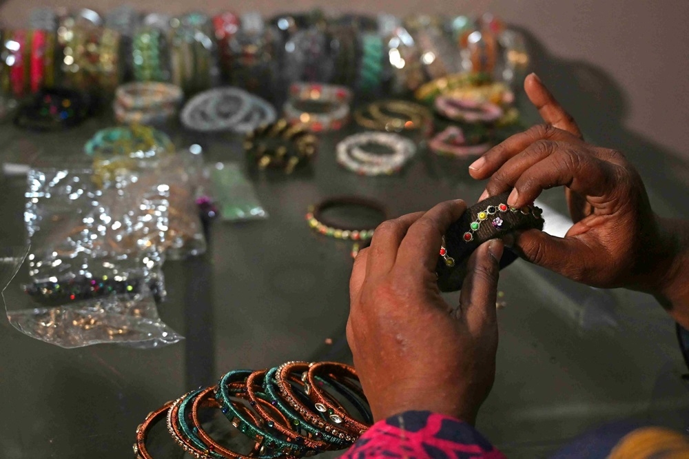 Talat Zahid adds decorative elements to bangles at a home workshop in Hyderabad. ― AFP pic