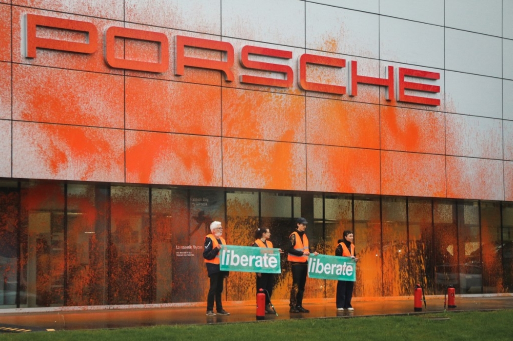 This handout photograph taken and released by Liberate and Renovate Switzerland in Lausanne on April 9, 2024, shows climate activists posing after spraying with orange paint the building a sales center’s building of German carmaker Porsche. Activists sprayed a Swiss Porsche outlet with orange paint in a campaign to ‘Liberate Switzerland’ from cars, following a historic ruling by Europe’s top rights court faulting the country for climate inaction. — Liberate and Renovate Switwerland / AFP pic 