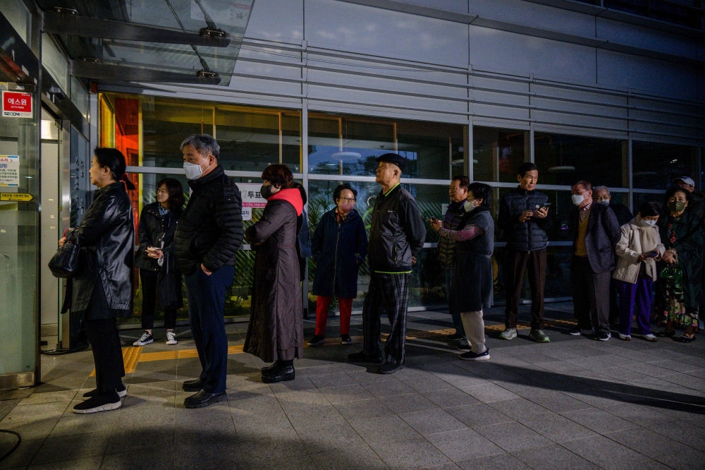 People line up at a polling station before voting begins in Seoul early on April 10, 2024. — AFP pic