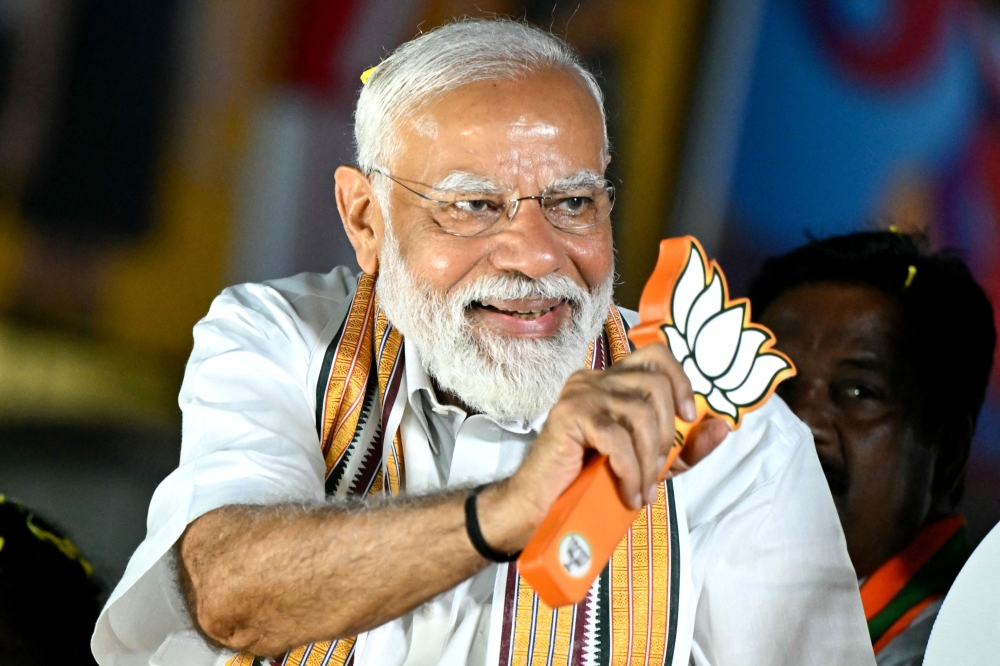 Narendra Modi, India's Prime Minister and leader of the ruling Bharatiya Janata Party (BJP) holds the party symbol during a road show at an election campaign held ahead of the country's upcoming general elections, in Chennai April 9, 2024. — AFP pic