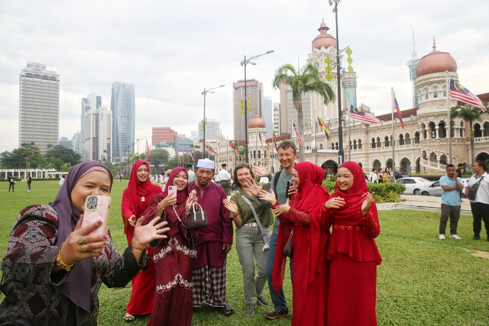 People pose of pictures at Dataran Merdeka during Hari Raya Aidilfitri Day 1, in Kuala Lumpur April 10, 2024. 
