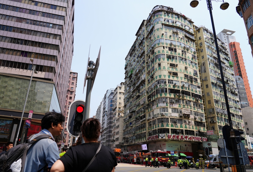 People look on near the residential building where a fire broke out in a gym, in Kowloon district, in Hong Kong April 10, 2024. — Reuters pic