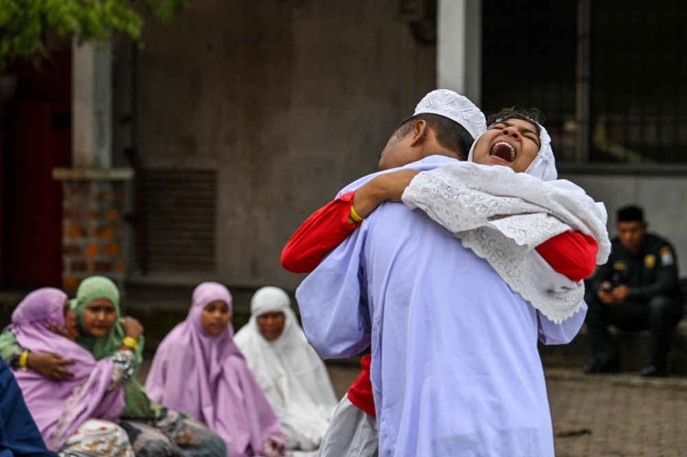 Rohingya refugees embrace each other after taking part in Eid al-Fitr prayers, marking the end of the holy month of Ramadan, at a temporary shelter in Meulaboh, Indonesia's Aceh province April 10, 2024. — AFP pic