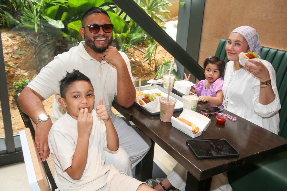 Syafiq Zain and his family enjoy their favourite burger brand after two years since they last had it in Singapore. — Picture by Choo Choy May 