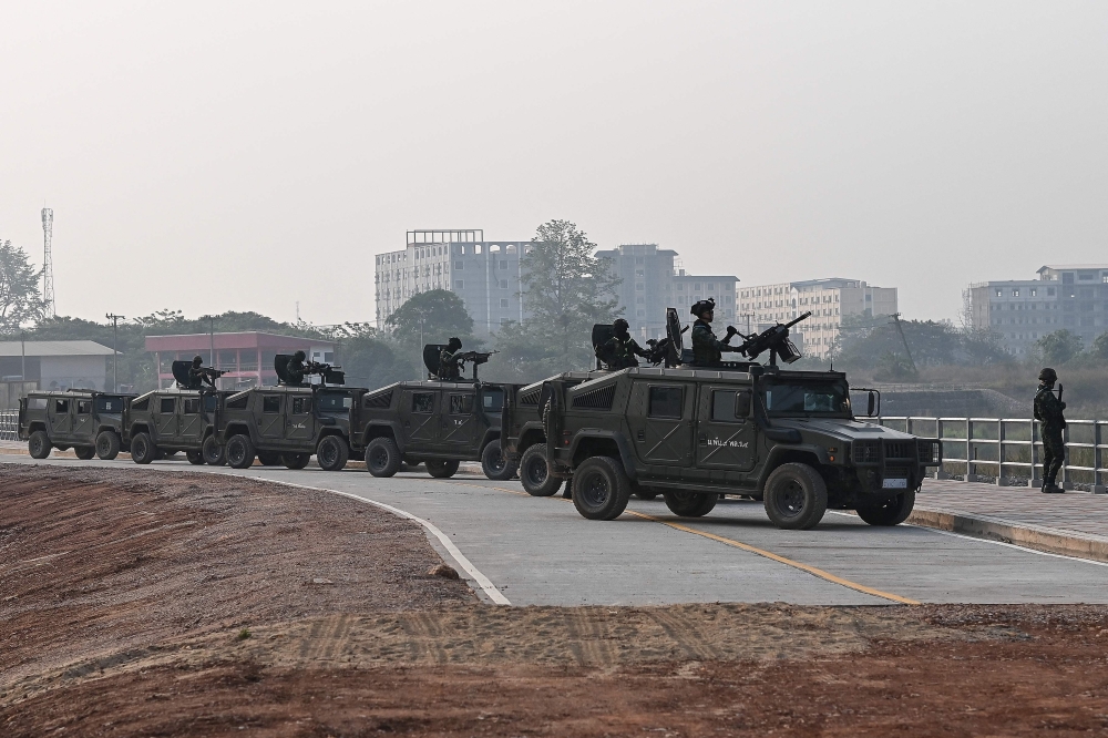 Thai military personnel keep watch from atop armoured vehicles along the Moei river on the Thai side, next to the second Thai-Myanmar Friendship Bridge in Mae Sot. — AFP pic
