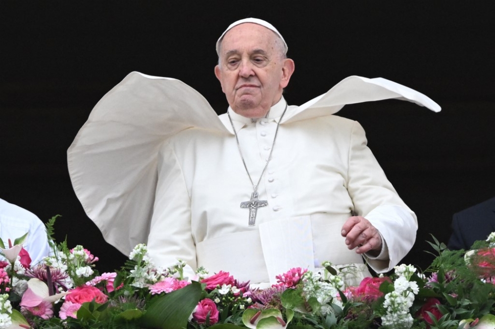 The wind lifts Pope Francis mantilla as he stands at the central loggia of St Peter's basilica during the Easter 'Urbi et Orbi' message and blessing to the City and the World as part of the Holy Week celebrations, in the Vatican on March 31, 2024. Pope Francis, 87, will travel to Indonesia, Papua New Guinea, East Timor and Singapore in September, the Vatican announced on April 12, 2024. — AFP pic