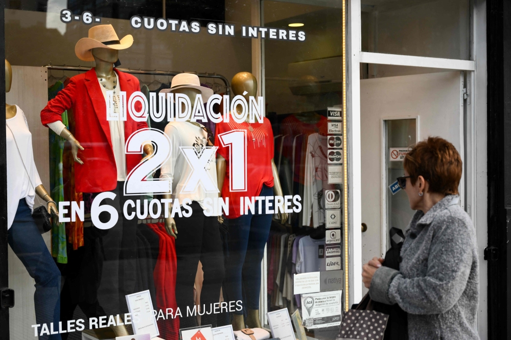 A woman looks at clothes displayed in a store with a 'liquidation' sign in Buenos Aires on April 12, 2024. ― AFP pic