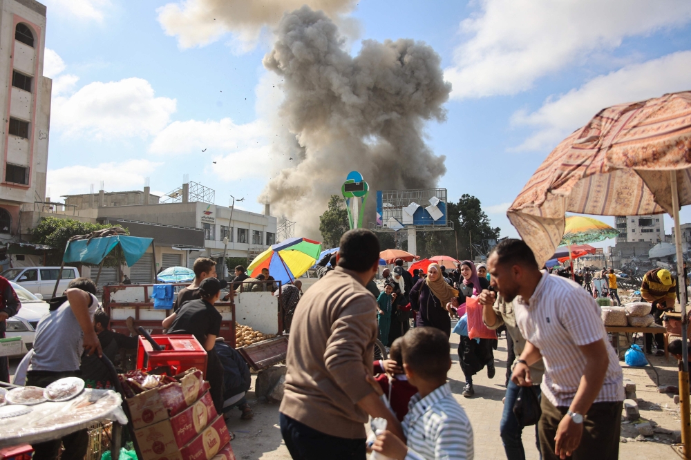 Palestinians look at smoke billowing during Israeli bombardment on the Firas market area in Gaza City on April 11, 2024, amid the ongoing conflict between Israel and the Palestinian Hamas group. — AFP pic
