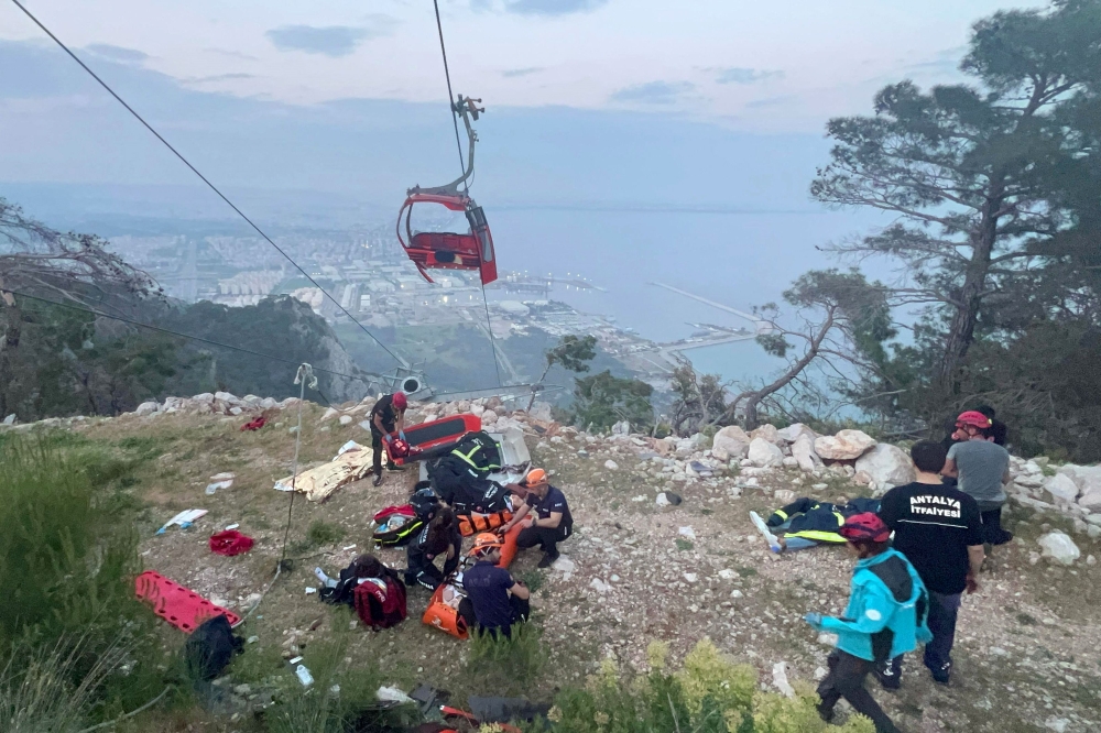 This handout photograph taken and released on April 12, 2024 by Turkish news agency DHA (Demiroren News Agency) shows rescue teams conducting a rescue operation and helping injured people after a cable car cabin crashed into a fallen cable pole in Konyaalti district of Antalya. — Handout by Demiroren News Agency via AFP