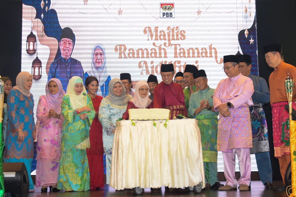 Juma’ani and Abang Johari cut a cake during the event. From front second left are Rubiah, Mohd Naroden, and Abu Bakar. — The Borneo Post pic
