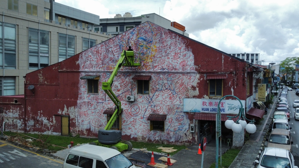 Renowned mural artist Leonard Siaw Quan Cheng works on his third major project, inspired by a traditional herbal tea shop at Jalan Padungan in Kuching. — Picture by Roystein Emmor via The Borneo Post