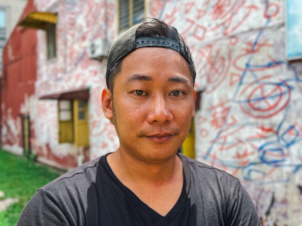 Siaw poses in front of the doodle grid wall, serving as the canvas for his third Padungan mural next to the Tun Jugah Shopping Centre. — Picture by Roystein Emmor via The Borneo Post