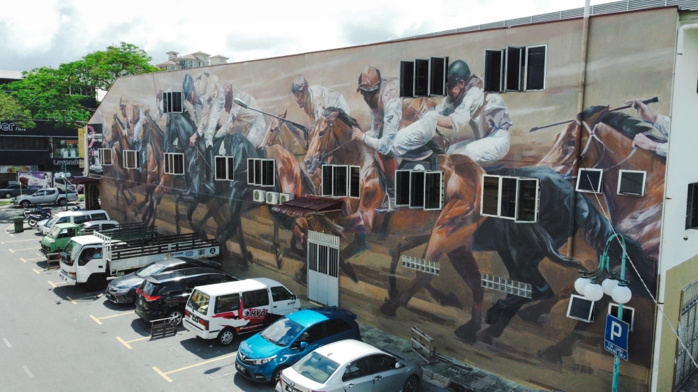 Picture shows Siaw’s second mural at Jalan Padungan, capturing an exhilarating, finely-detailed horse-racing scene. — Picture by Roystein Emmor via The Borneo Post