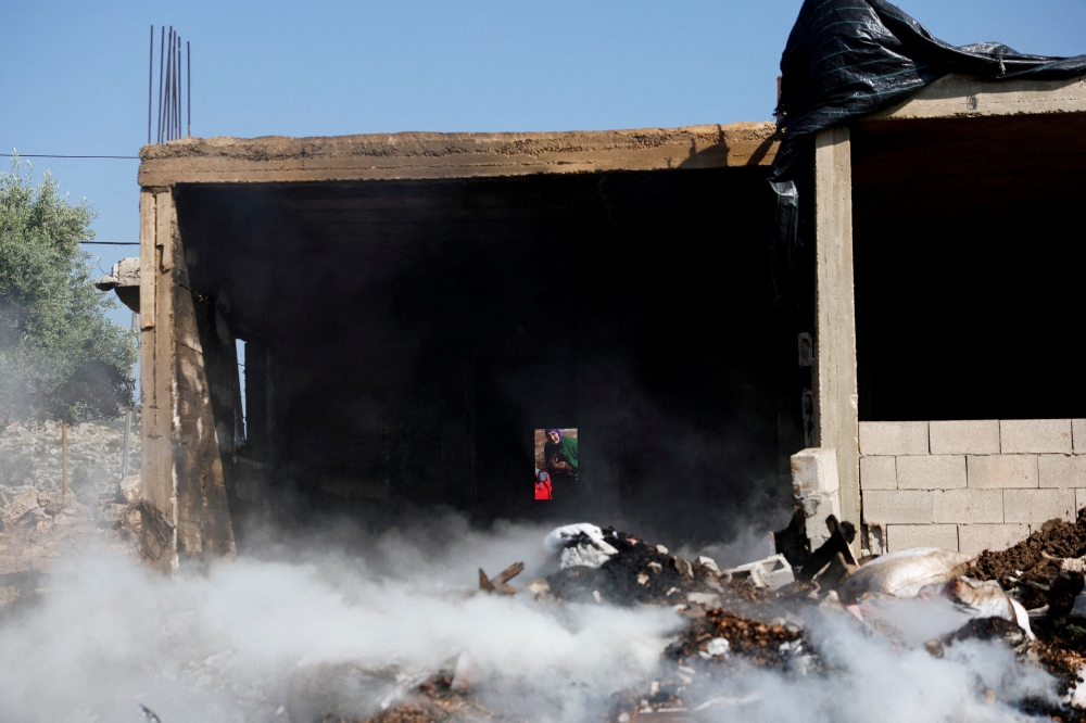 A Palestinian woman inspects the damage to her house after Israeli settlers attacked the village of al-Mughayyer, in the Israeli-occupied West Bank, April 13, 2024. — Reuters pic