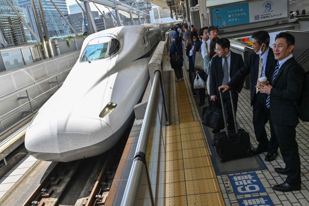 Passengers wait on the platform as a Kodama bullet train, or 