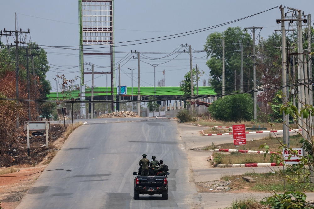Soldiers from the Karen National Liberation Army (KNLA) patrol on a vehicle, next to an area destroyed by Myanmar's airstrike in Myawaddy, the Thailand-Myanmar border town under the control of a coalition of rebel forces led by the Karen National Union, in Myanmar, April 15, 2024. — Reuters pic
