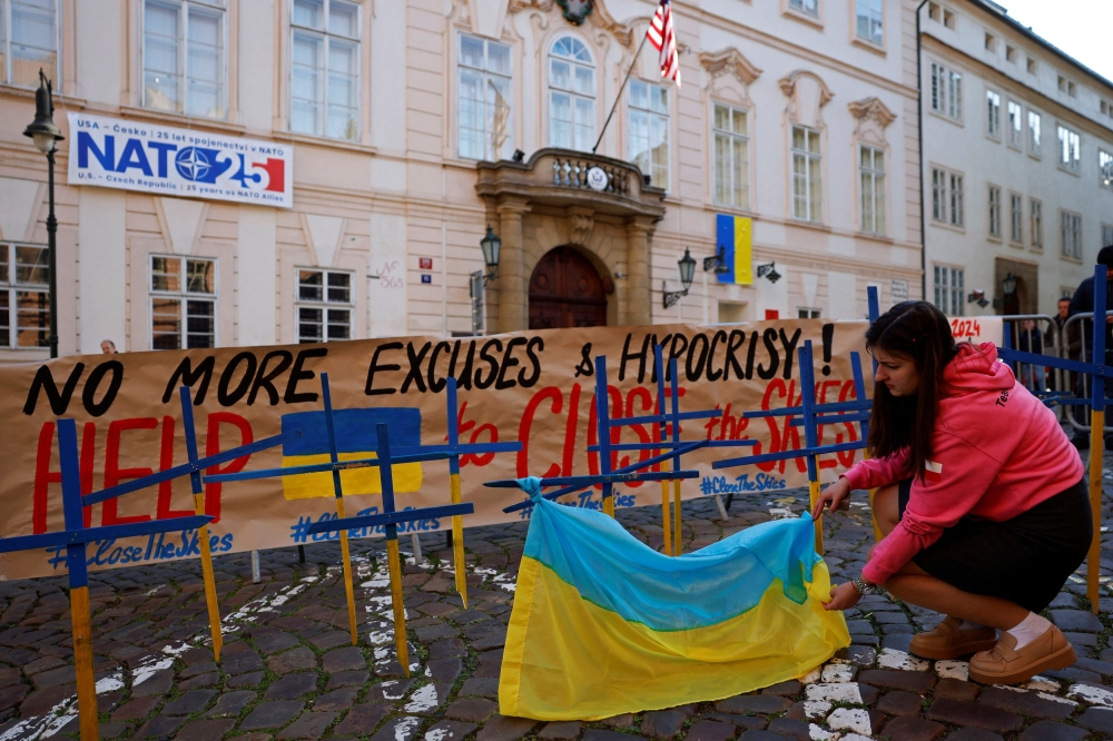A wooden crosses in colours of the Ukrainian national flag are placed in front of the US embassy during a protest in Prague. — Reuters pic