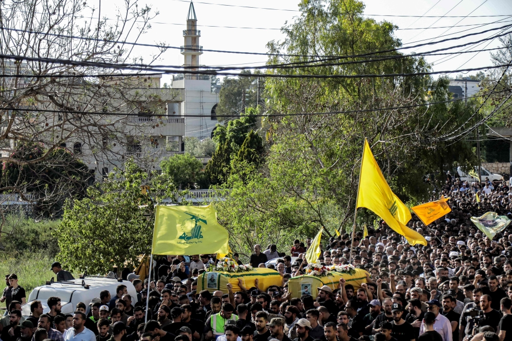 Mourners carry the bodies of Hezbollah members Ismail Baz and Mohamad Hussein Shohury, who were killed in an Israeli strike on their vehicles. — AFP pic