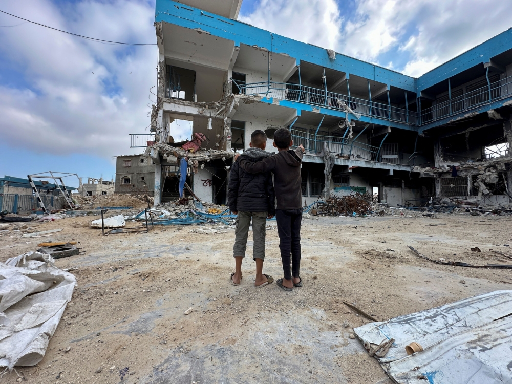 Palestinian school children Abed Al-Qara and Muhammad Al-Fajem view their school which was destroyed during Israel's military offensive, amid the ongoing conflict between Israel and Hamas, in Khan Younis in the southern Gaza Strip, April 14, 2024. — Reuters pic