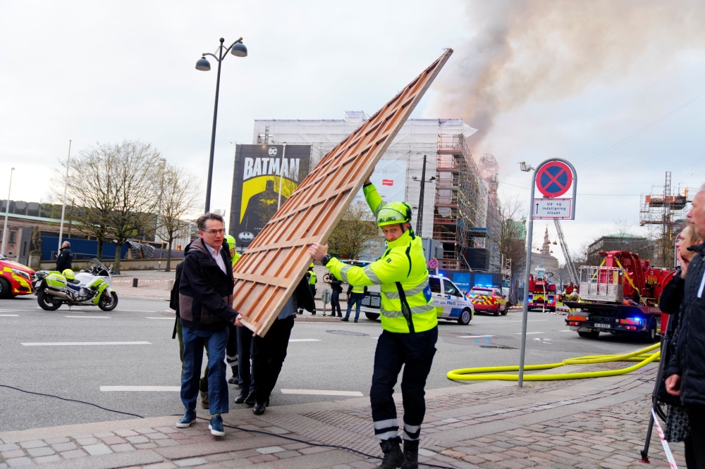 Former Danish Minister of Culture and current CEO of Danish Business (Dansk Erhverv), Brian Mikkelsen, assists with the evacuation of paintings after a fire broke out at the Old Stock Exchange, Boersen, in Copenhagen, Denmark April 16, 2024. — Ritzau Scanpix/Ida Marie Odgaard pic via Reuters 