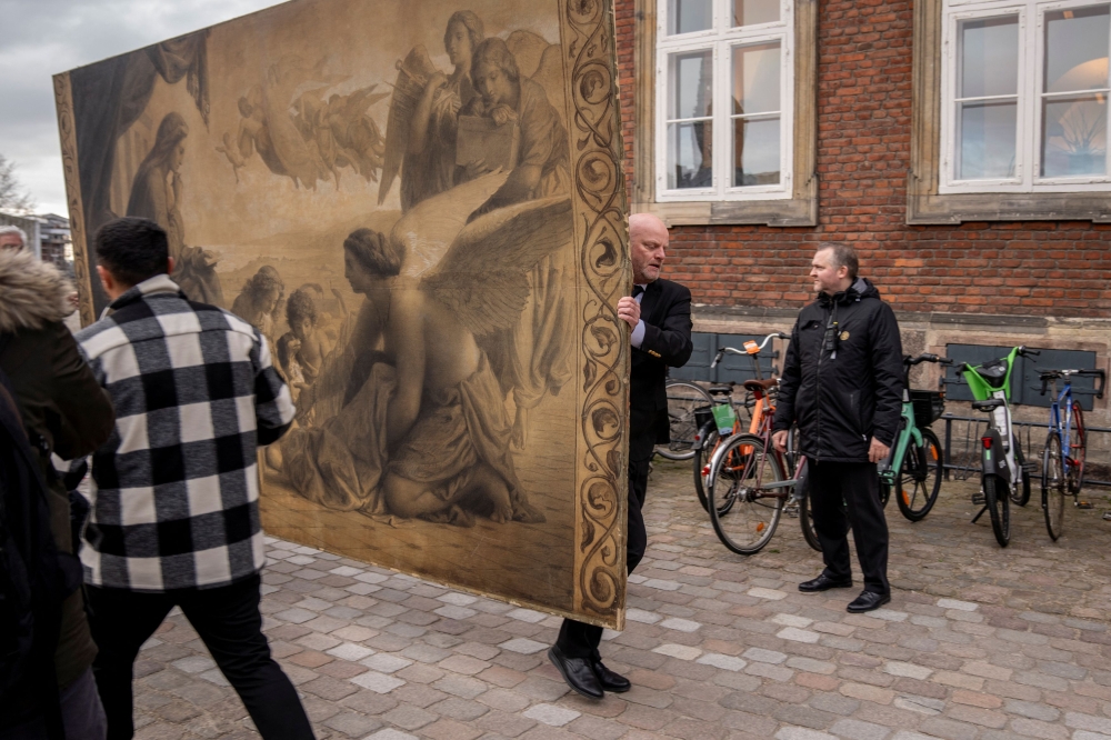 People carry a historic painting out of the Old Stock Exchange, Boersen, during a fire in the historic building, in Copenhagen, Denmark, April 16, 2024. — Ritzau Scanpix/Ida Marie Odgaard pic via Reuters 