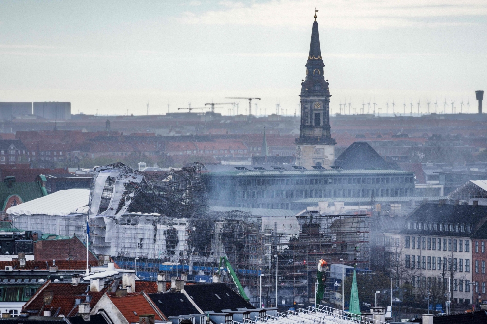 This photo taken on April 18, 2024 shows smoke rising from the site of the historic former stock exchange Boersen after the collapse of the facade towards the castle square and Boersgade street in Copenhagen, two days after a fire broke out that burned about half of the 17th century building. — AFP pic