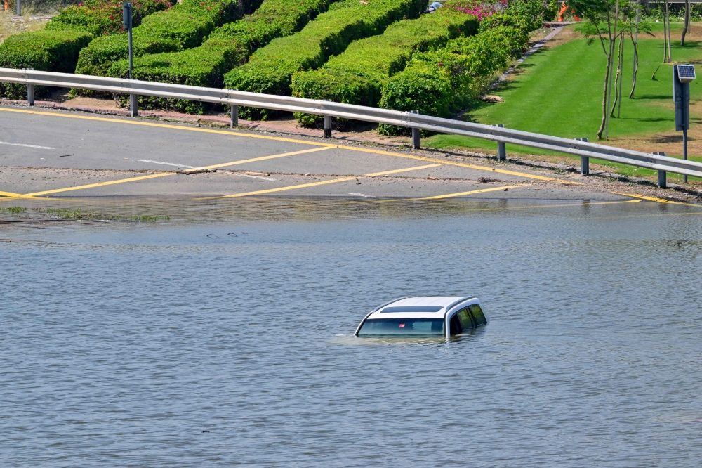 A car is stranded on a flooded street in Dubai following heavy rains on April 18, 2024. Dubai's giant highways were clogged by flooding and its major airport was in chaos as the Middle East financial centre remained gridlocked on April 18, a day after the heaviest rains on record. — AFP pic