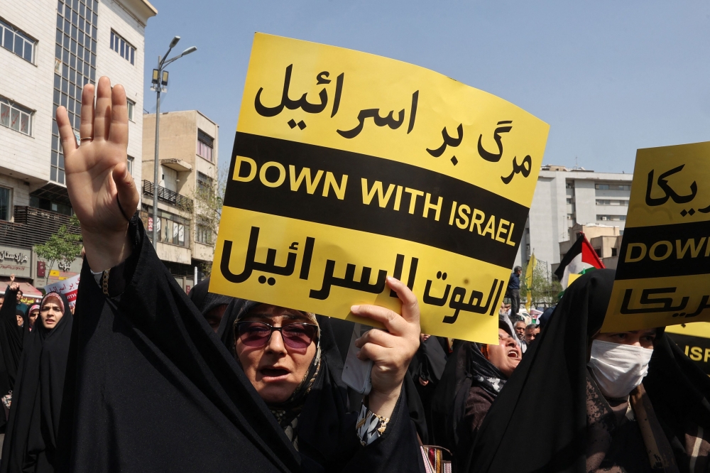 Iranians wave the flags of Palestine and Iran they gather during an anti-Israel demonstration after the Friday noon prayer in Tehran on April 19, 2024. ― AFP pic