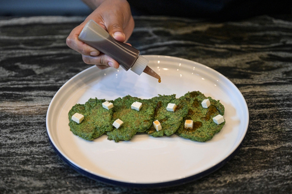 Melissa Castro prepares a dish using the peels, leaves, and stems of vegetables and fruits in a restaurant laboratory where a team of chefs and nutritionists investigate culinary techniques to optimise food in Lima April 11, 2024. — AFP pic