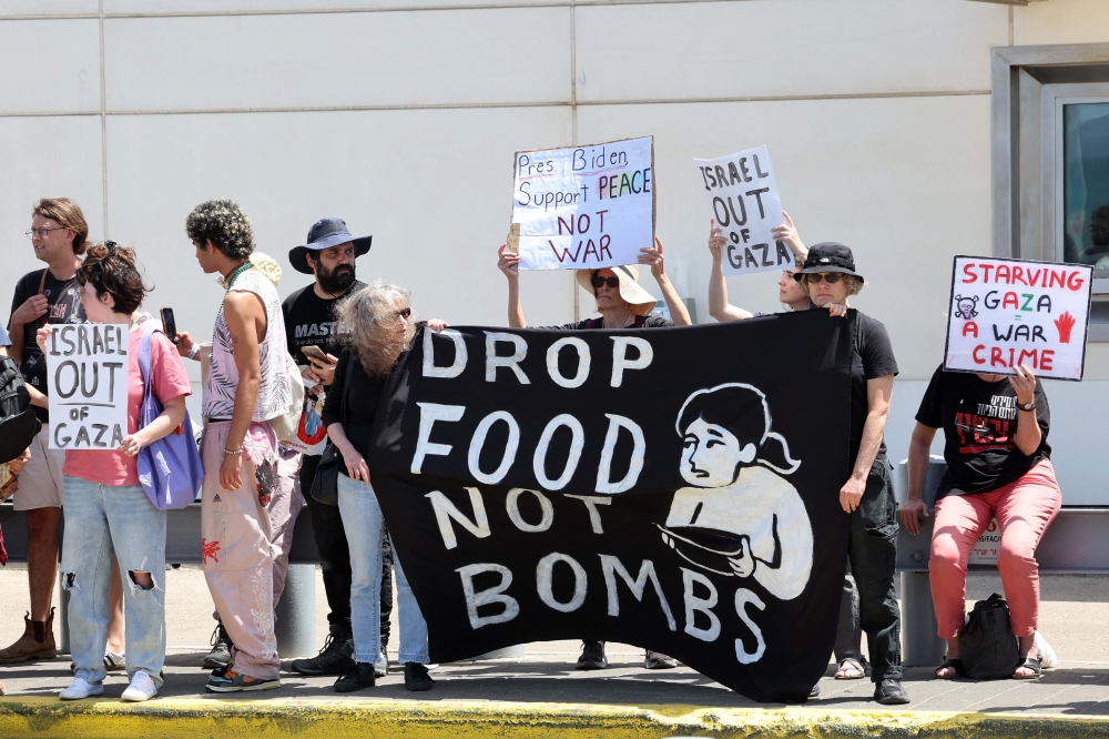 Israeli left wing activists deploy a banner and lift placards as they demonstrate in front of the Branch Office of the US embassy in Tel Aviv, to demand the US to stop arming Israel and an end to the war in the Gaza Strip, on April 19, 2024, amid the ongoing conflict between Israel and the Palestinian militant Hamas movement. ― AFP pic
