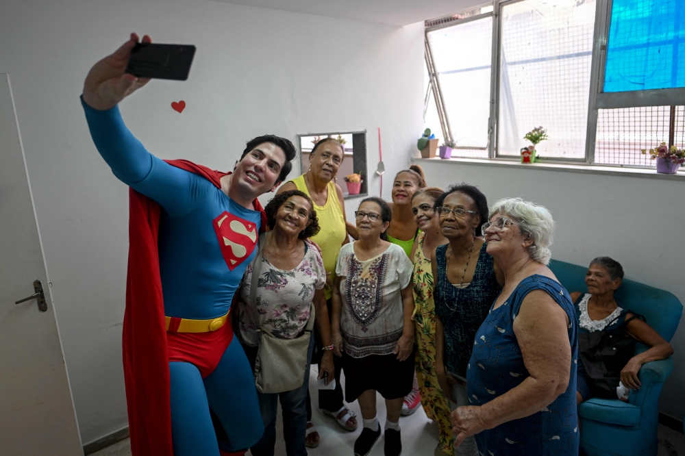 Leonardo Muylaert, 36, known as the Brazilian Superman, takes a selfie with a group of ladies at the Association of Parents and Friends of Neurodivergent People (APAE-RIO) in the Tijuca neighborhood in Rio de Janeiro, Brazil, on March 18, 2024. — AFP pic