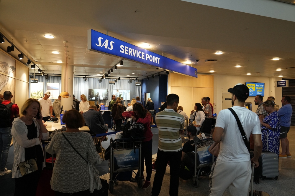 File photo of flight passengers standing at a service point of Scandinavian airline SAS at Terminal 3 of the Copenhagen airport on July 2, 2022. ― AFP pic