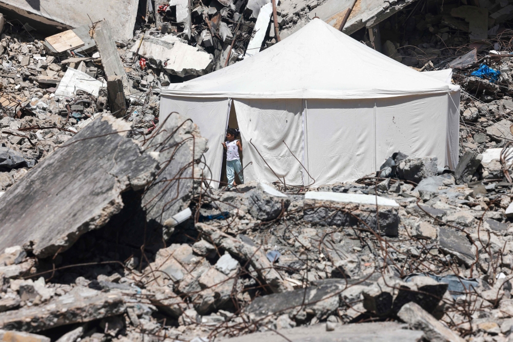 A displaced Palestinian stands at the entrance of a tent set up amid the rubble of a building damaged during Israeli bombardment in Rafah. — AFP pic