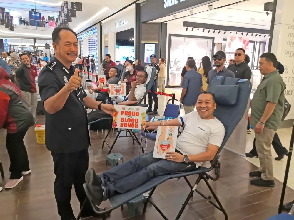 Sabah Police Commissioner Datuk Jauteh Dikun (left) poses for a photo with a member of the public who donated blood at the Crime Prevention Carnival and Blood Donation Campaign in conjunction with the 217th Police Day celebration at Imago Shopping Mall April 21, 2024. — The Borneo Post pic 