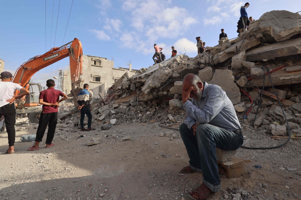 A Palestinian man wait for news of his daughter as rescue workers search for survivors under the rubble of a building hit in an overnight Israeli bombing in Rafah. — AFP pic