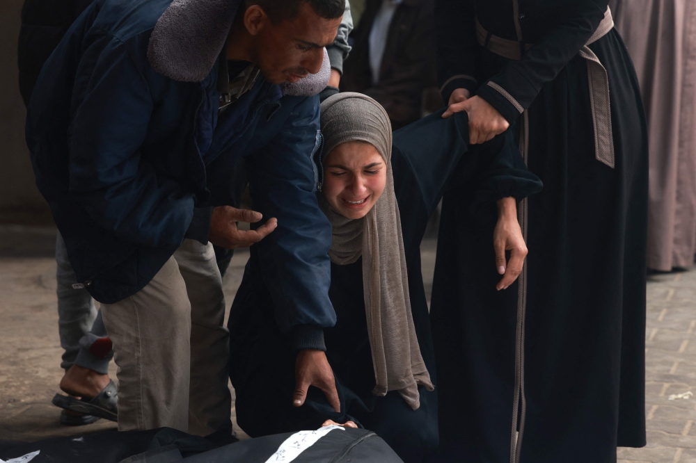 Palestinians mourn over the bodies of relatives killed in Israeli bombardment, at the al-Najar hospital in Rafah. — AFP pic