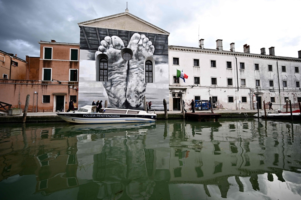 A mural by artist Maurizio Cattelan is seen outside Giudecca Women's Prison hosting the Holy See pavilion during the pre-opening of the 60th Venice Biennale art show, on April 18, 2024 in Venice. — AFP pic
