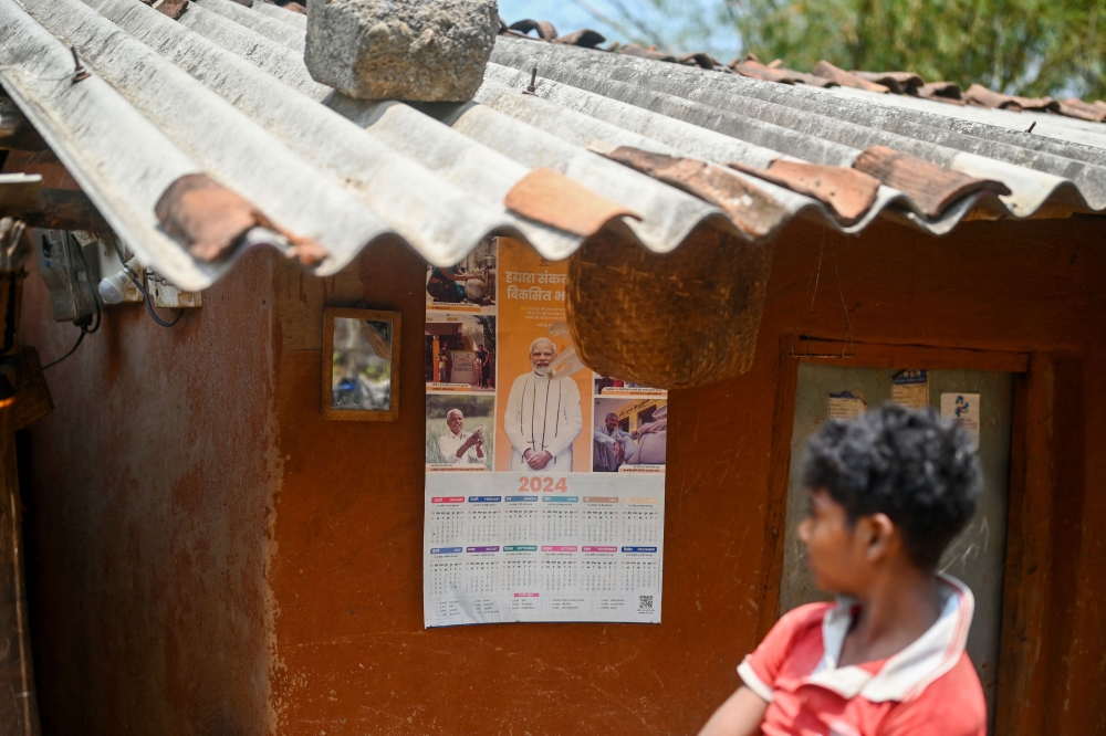 A boy looks at a calendar with a portrait of India's Prime Minister Narendra Modi in Tatem village some 43 Km from Dantewada town in Chhattisgarh state on April 16, 2024, ahead of India's national elections. — AFP pic