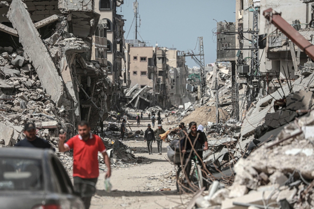 Palestinians walk along a road lined with destroyed buildings in Khan Yunis in the southern Gaza Strip on April 22, 2024 amid the ongoing conflict in the Palestinian territory between Israel and Hamas. — AFP pic