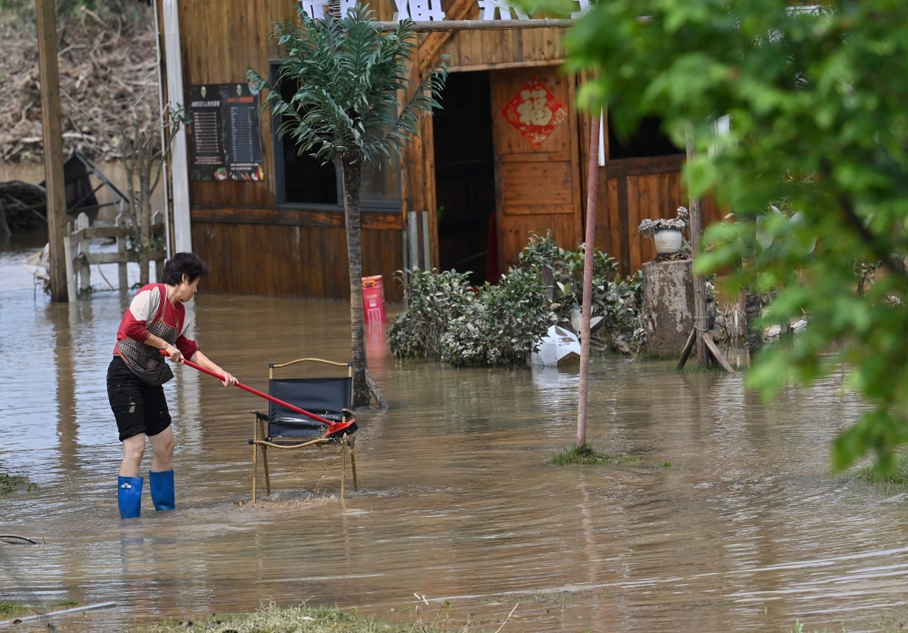 A woman cleans a chair after torrential rains flooded Qingyuan. — AFP pic