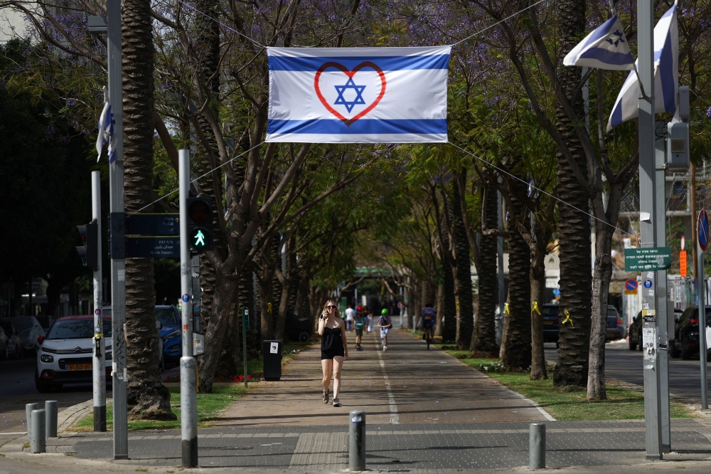 A woman walks near an Israeli flag with a heart symbol, amid the ongoing conflict in Gaza between Israel and Hamas, in Tel Aviv, Israel April 23, 2024. — Reuters pic