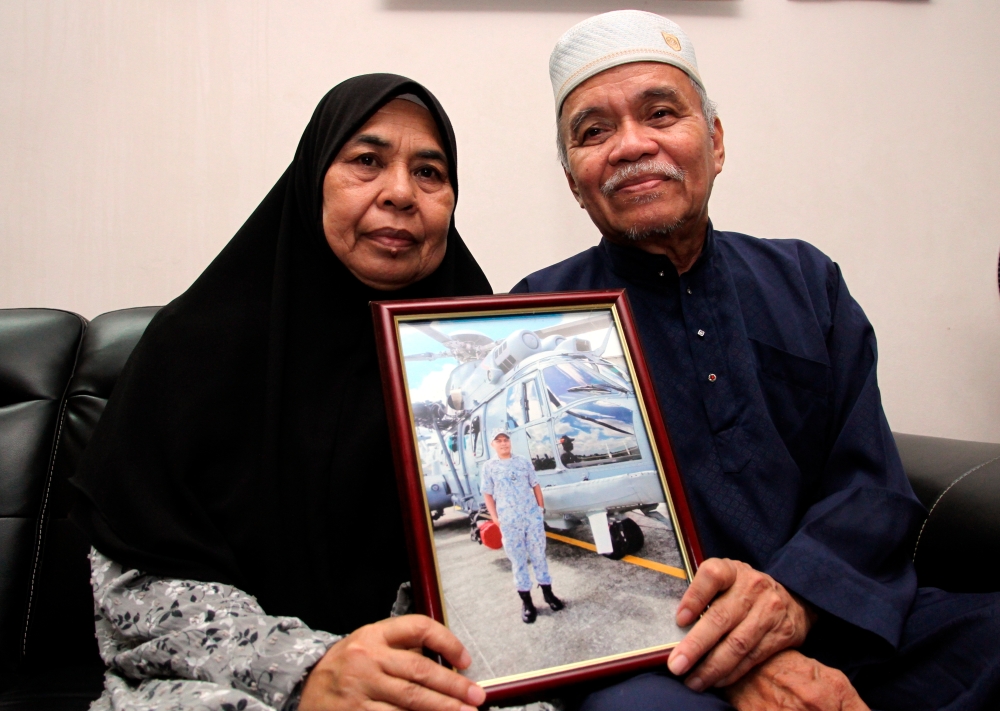Mohd Termizi Abdul Ghani, 68, and his wife, Hasnah Yasim, 67, hold a picture of their late son Warrant Officer II TMK Mohd Shahrizan Mohd Termizi, at their home in Taman Bunga Tanjung Lekir, Lumut, April 24, 2024. — Bernama pic 
