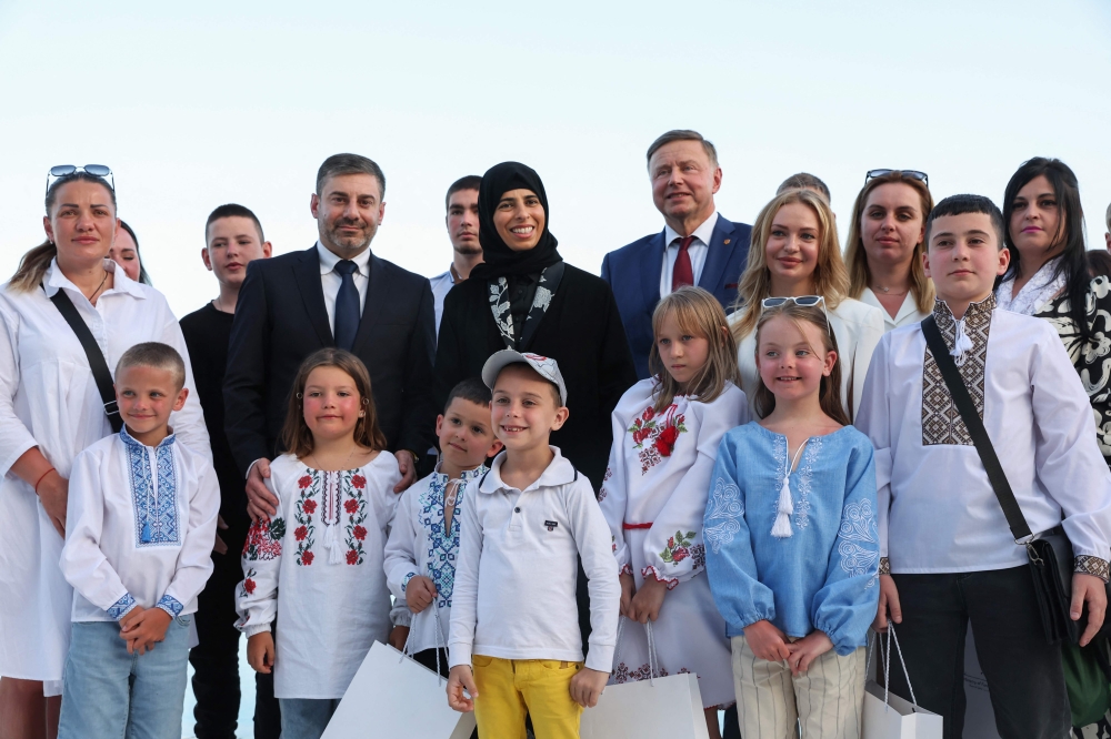 Qatari Minister of State for International Cooperation Lolwah Al-Khater (centre) and Human Rights Commissioner in the Ukrainian Parliament Dmytro Lubinets (centre left) pose for a picture with Ukrainian children and their families in Doha on April 24, 2024. — AFP pic